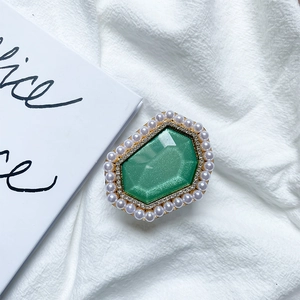 Close-up of green hexagonal gemstone phone stand with pearls and rhinestones