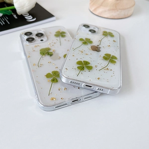 Dettaglio custodia iPhone con veri quadrifogli verdi e foglie d'oro in resina trasparente