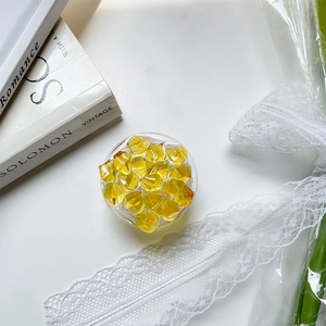 Detail of yellow faceted gemstone phone socket holder on white lace and floral background