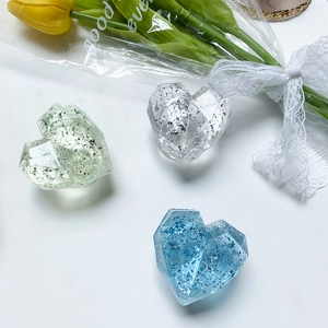 Detail view of heart-shaped glitter phone grips in green, blue, and silver on marble