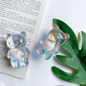 Détail de deux supports de téléphone ours holographiques avec cœurs blancs posés sur un livre