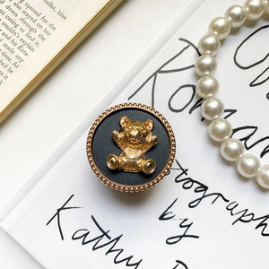 Close-up of golden 3D bear phone grip with vintage metal texture and pearl details