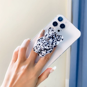 Hand holding phone with a marble pattern bear-shaped grip stand attached to the back