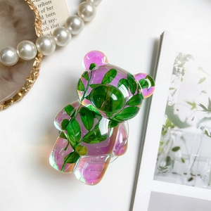 Detailed view of iridescent bear phone grip with embedded real green plant leaves