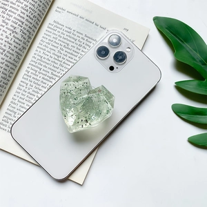 Macro shot of heart-shaped glitter phone grip with resin texture on white phone