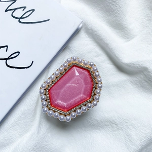 Close-up of pink hexagonal gem phone grip with pearl and rhinestone accents