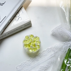 Detail of round mint green collapsible phone grip with crystal texture on white desk