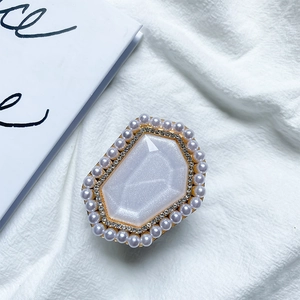 Close-up of pearl and rhinestone phone grip with a hexagonal white gem on gold base