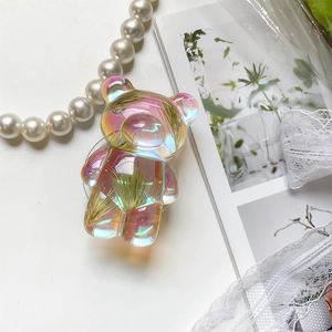 Detailed macro view of iridescent pink bear phone socket with embedded dried flowers