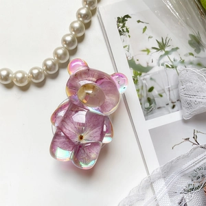 Detail of bear shaped phone grip with purple dried flower and iridescent edge effect