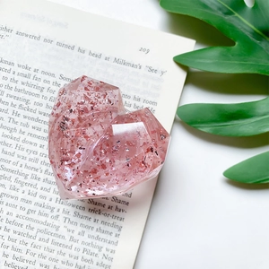 Detail view of heart-shaped glitter phone grip with pink sequins on vintage book background