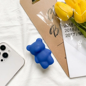 Navy blue 3D gummy bear phone grip stand with a matte finish on a white fabric background