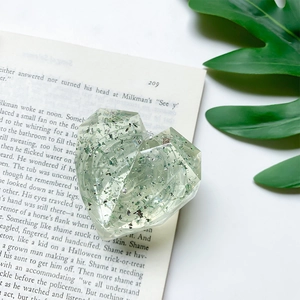 Detail of a green heart-shaped resin phone socket with silver glitter on book pages