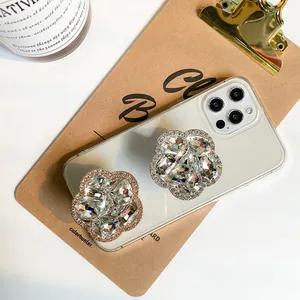 Detail of luxury rhinestone flower phone grips on a white case over a vintage board