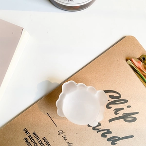 Top-down shot of minimalist matte white crab phone grip on a brown clip board desk