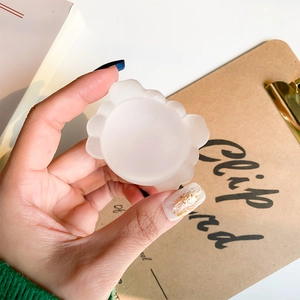 Detailed view of white translucent crab-shaped phone grip held against a desk background