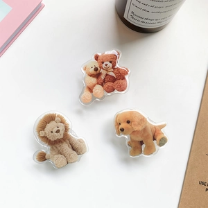 Detailed view of creative acrylic teddy bear and lion phone grips on a white table