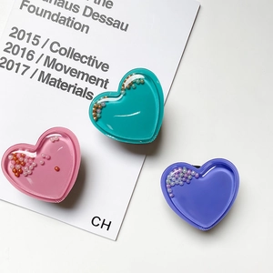 Detail showing heart-shaped liquid quicksand phone grips with colorful microbeads
