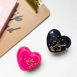 Detail of heart-shaped liquid quicksand phone sockets in pink and black on a desk