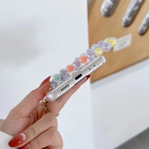 Close-up of transparent phone case featuring a vibrant colorful beaded charm strap
