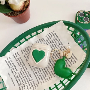 Detail of cream silicone AirPods case with green 3D heart and pearl charm pendant
