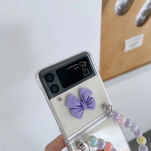 Detail view of transparent Z Flip case with a purple 3D bow and iridescent beaded chain