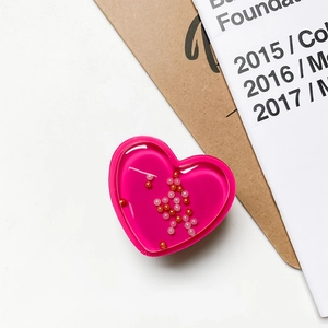 Macro detail of a pink heart liquid quicksand phone socket with moving beads and fluid