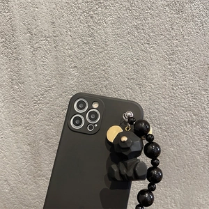 Detail of matte geometric bear pendant and black beaded wrist strap for iPhone case