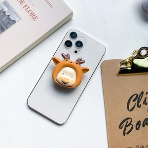 Close-up of cute cartoon pig phone grip with deer antlers on a white smartphone