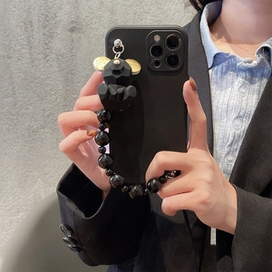 Detail of matte black iPhone case featuring a geometric bear charm with golden accents