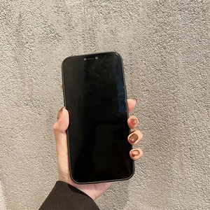 Close-up of a matte black phone case for iPhone held by a hand against a gray wall