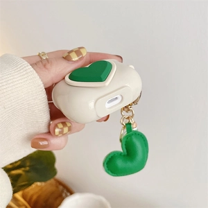 Detailed view of cream AirPods Pro silicone case with 3D green heart and matching charm