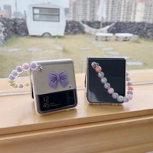 Clear Galaxy Z Flip case featuring a 3D bow and colorful beaded chain strap detail