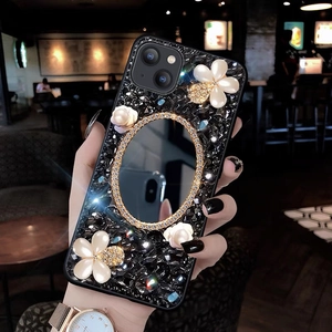 Close-up of luxury iPhone case featuring black crystals, pearl flowers and a vanity mirror
