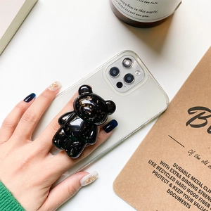 Detailed view of black 3D bear phone grip with gold flakes on a transparent case