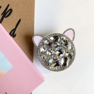 Close-up of luxury rhinestone cat-shaped phone grip with pink ears on a white desk