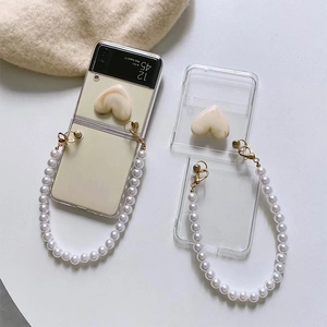 Detail of clear Z Flip case with cream heart ornament and white pearl handle strap