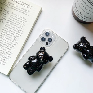Close-up of a 3D bear phone grip with gold foil flakes on a transparent phone case