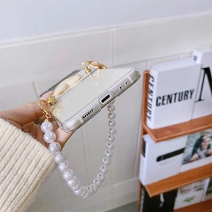 Detail of transparent phone case with large white pearl strap and gold metal clasps