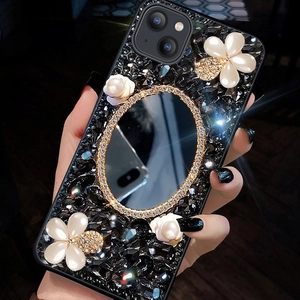 Close-up of luxury iPhone case with black crystals, pearl flowers, and makeup mirror