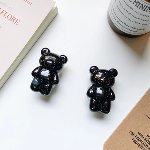 Detail of glossy black bear phone grips with gold foil flakes on a minimalist white surface