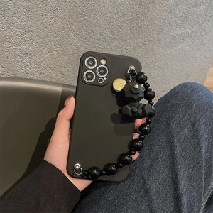 Matte black iPhone case with beaded wrist strap and geometric bear charm, handheld view