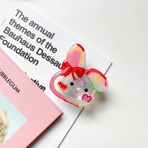 Détail du support de téléphone lapin rose avec base transparente sur un bureau chic