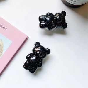Macro detail of black resin bear phone grip featuring luxury embedded gold leaf elements