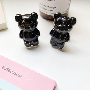 Close-up of bear-shaped phone grips made of black resin with luxury gold foil flakes