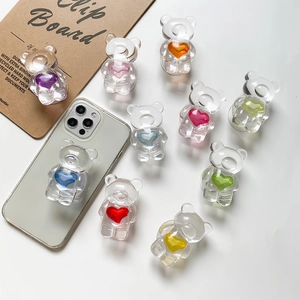 Close-up of colorful resin bear phone grips with embedded hearts on white surface