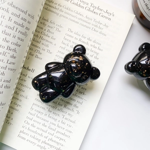 Detailed close-up of glossy black bear phone grip with decorative gold foil flakes
