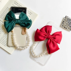 Close-up of luxury phone case with a large satin bow and pearl bracelet handle detail