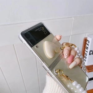 Detail of transparent Z Flip case with cream 3D heart grip and large pearl bead strap