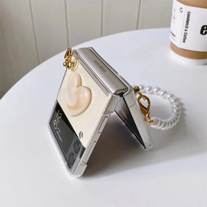 Detailed view of cream-colored folding phone case with heart relief and pearl wrist strap
